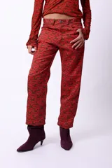 Pantalón de corte recto con largo al tobillo, confeccionado con una estampa geométrica sublimada en tonos marrón y rojo. Presenta tiro medio y un calce cómodo.