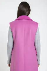 Chaleco largo de corte sastre en color fucsia, confeccionado en material tipo corderoy con interior y solapas de corderito al tono. Presenta cierre frontal cruzado con botones oscuros y bolsillos laterales con solapa.