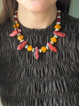 Collar corto con cuentas de cristal checo, piedras naturales y cuentas reconstituidas en tonos rojo, naranja y turquesa. Cuenta con cierre de gancho y cadena de acero quirúrgico para ajustar el largo.