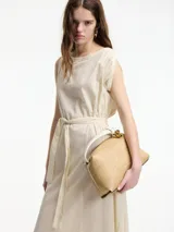 Vestido midi de algodón color crudo, con diseño tipo túnica, cuello redondo y lazo ajustable en la cintura para entallar la silueta. Presenta detalles de bordado sutil en el cuello y las sisas.
