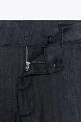Jeans de tiro medio con corte flare y largo completo. Presenta bolsillos delanteros, cierre con cremallera, botón y ganchos metálicos.