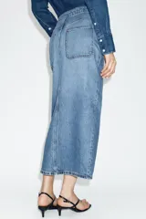 Falda midi de denim azul con diseño cruzado, cierre frontal con botones metálicos y bolsillos delanteros.