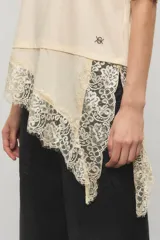 Remera negra de corte oversize, con escote redondo, mangas cortas y detalle de tajo irregular con terminación en puntilla en el ruedo. Confeccionada en jersey de algodón.