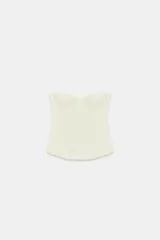 Corsé color crema con aros y varillas, confeccionado en tejido elástico. Presenta escote corazón y diseño sin hombros.