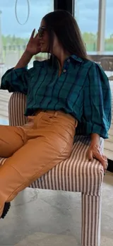 Camisa de corte oversize con estampado a cuadros en tonos verde y azul. Presenta mangas abullonadas con puños elásticos y cierre frontal con botones.