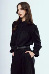 Camisa de manga larga con patrón a cuadros en tonos marrones, corte clásico con cuello camisero, botonadura frontal y detalles fruncidos en el canesú delantero.
