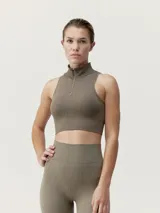 Top cropped deportivo color marrón, de sujeción media, con cuello alto y cierre frontal. Presenta un diseño de nervios que favorecen la silueta y una abertura en la espalda para mayor transpirabilidad.
