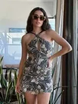 Vestido corto negro con estampado de plumas doradas, escote en V, breteles finos cruzados en la espalda, cut-outs laterales y volado en el ruedo.