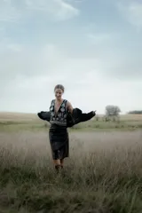 Pollera midi de eco cuero color beige, de corte recto y tiro alto, con costuras verticales decorativas y detalle de cinturón fino con flecos.