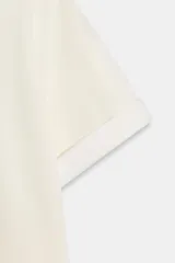 Camiseta de corte regular fit y color blanco, con cuello redondo, mangas cortas con vuelta y bajo recto.
