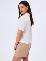 Camisa de manga corta color blanco, confeccionada en mezcla de viscosa, poliamida y lino, con cuello camisero y cierre frontal de botones.