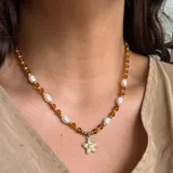 Collar corto con cuentas de cristal color ámbar, perlas de río blancas y dije de flor dorada.