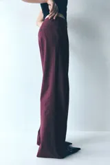 Pantalón de vestir de pierna ancha, color bordó oscuro, con finas rayas verticales en tono similar. Presenta cintura clásica con cierre de botón y bolsillos al bies.