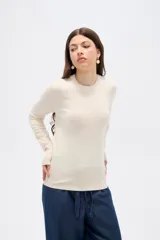 Sweater de lyocell al cuerpo, con cuello redondo a la base y mangas largas con detalle de botones en los puños.