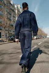 Chaqueta estilo bomber de Zara confeccionada en tejido denim azul oscuro. Presenta cuello solapa, cierre frontal con cremallera, bolsillos delanteros con solapa y bajo elástico que le otorga un ajuste ceñido en la cintura.