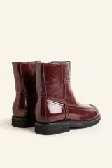 Bota corta de cuero vacuno con acabado charol brillante, diseño de punta cuadrada y suela de caucho con pequeña plataforma.