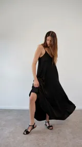 Vestido largo de satén negro, con diseño de solera, escote en V y breteles finos ajustables. Presenta un corte holgado y fluido.