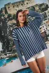Buzo de punto liviano con diseño de rayas verticales en tonos azul y marino, con acabado brillante de lurex. Presenta cuello con medio cierre frontal, mangas largas y corte oversized con caída fluida y terminaciones al corte.