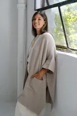 Poncho abierto de tejido de punto en color visón, con diseño holgado, mangas cortas y bolsillos frontales aplicados.