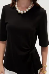 Remera negra de manga corta, con cuello redondo y diseño holgado con detalle de lazo para anudar en la cintura.
