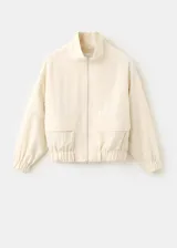 Chaqueta oversize color beige con cuello alto, cierre frontal de cremallera, bolsillos frontales con solapa y mangas largas.