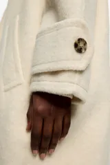 Abrigo de largo medio confeccionado en mezcla de lana doble faz, con diseño de doble botonadura frontal, cuello de solapa amplia y manga larga con trabillas en los puños. Presenta bolsillos laterales de vivo.