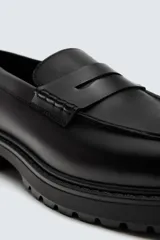 Mocasín de vestir negro con detalle de antifaz en la parte superior y suela track.