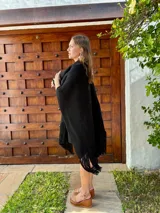 Ruana tejida en lana, de color negro, con diseño de flecos en los bordes inferiores.