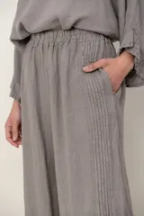 Pantalón palazzo de lino color blanco, con cintura elástica fruncida, bolsillos laterales y detalle de alforzas verticales en los laterales.