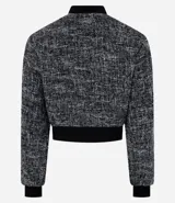 Campera bomber corta confeccionada en tweed con cuello alto, cierre frontal con cremallera, bolsillos y detalles en rib.