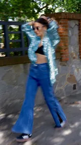 Pantalón de jean azul de tiro medio con spandex y detalle de botones metálicos en la parte inferior de la pierna.