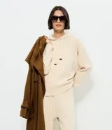 Buzo de punto con capucha y cordones ajustables con punteras metálicas. Presenta un diseño de corte regular, confeccionado en una mezcla de viscosa, poliéster y poliamida, ofreciendo una textura suave y cómoda.