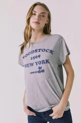 Remera gris melange de corte clásico y mangas cortas, con estampa frontal azul de Woodstock 1969 New York.