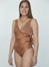 Malla enteriza con diseño cruzado tipo pareo, con un lado liso y otro con estampado floral. Presenta un lazo lateral para anudar y escote en V.