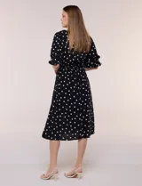 Vestido midi de calce holgado y caída fluida con escote en V cruzado, cintura elastizada fruncida y mangas cortas con volados superpuestos. Cuenta con un diseño estampado de flores grandes en tonos amarillo, blanco, azul marino y verde.