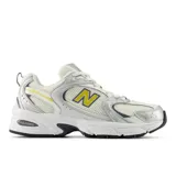 Championes New Balance modelo 530, de estilo retro inspirado en el running. Presentan una base de malla blanca con superposiciones en cuero sintético plateado y detalles en amarillo y azul oscuro. Incorporan tecnología de amortiguación ABZORB en la entresuela para mayor confort.