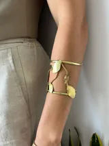Brazalete dorado con diseño de hojas y estructura abierta.