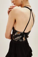Vestido corto negro con volados en la falda y escote halter. El corpiño es de lentejuelas con diseño animal print en tonos negro, dorado y plateado.