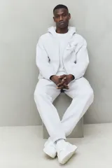 Pantalón deportivo de tejido de felpa color gris melange, con interior cepillado suave. Presenta cintura elástica con cordón de ajuste oculto, bolsillos laterales y un bolsillo trasero abierto. Las piernas terminan en puños acanalados.