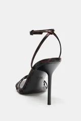 Sandalia de tacón alto fino con diseño de tiras finas en la parte delantera. Presenta un estampado animal print en tonos marrones y negros, con cierre de pulsera al tobillo mediante hebilla ajustable.