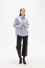 Camisa de algodón con diseño de rayas verticales finas en tonos neutros, corte holgado, cuello camisero y cierre frontal con botones.