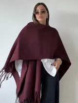 Ruana de paño color bordó con terminaciones de flecos en los extremos.