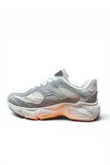 Championes deportivos en combinación de gris y beige, con diseño chunky de suela gruesa texturizada con detalles en tono anaranjado, cordones blancos y detalles laterales en relieve.
