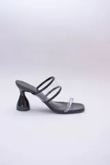 Sandalias negras con taco de forma geométrica y tiras transparentes.