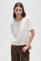 Remera de manga corta de viscosa, de corte al cuerpo, con cuello redondo y volados sutiles en los puños.