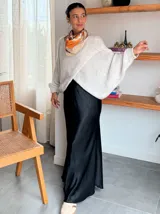 Sweater de punto gris con diseño cruzado en el frente, mangas largas con puños ajustados y corte holgado.