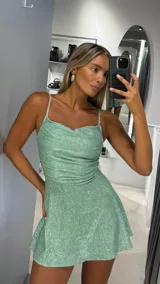 Vestido corto verde menta con brillos, escote drapeado, tirantes finos y falda acampanada.