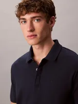 Chomba de manga corta Calvin Klein confeccionada en algodón interlock, con cuello clásico y cierre frontal de botones. Presenta un diseño liso en color azul marino con el logo de la marca sutilmente bordado en el pecho.