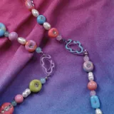 Collar de cuentas de colores pastel con dijes de formas abstractas y perlas de río.