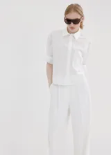 Camisa blanca de corte recto con mezcla de algodón y lyocell, adorno de perlas, cuello camisero, manga larga con puños abotonados y cierre delantero con botones ocultos.